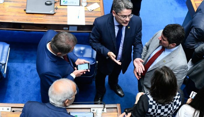 O relator do projeto, Alessandro Vieira (gravata azul), conversa no Plenário com Marcos do Val (gravata vermelha) e outros senadores (Marcos Oliveira/Agência Senado)